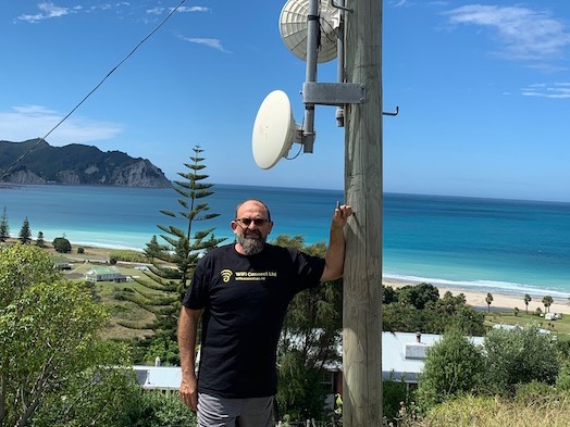 Image of WiFiConnect Director, Ivan Lomax, next to a WiFi repeater in Tokomaru Bay